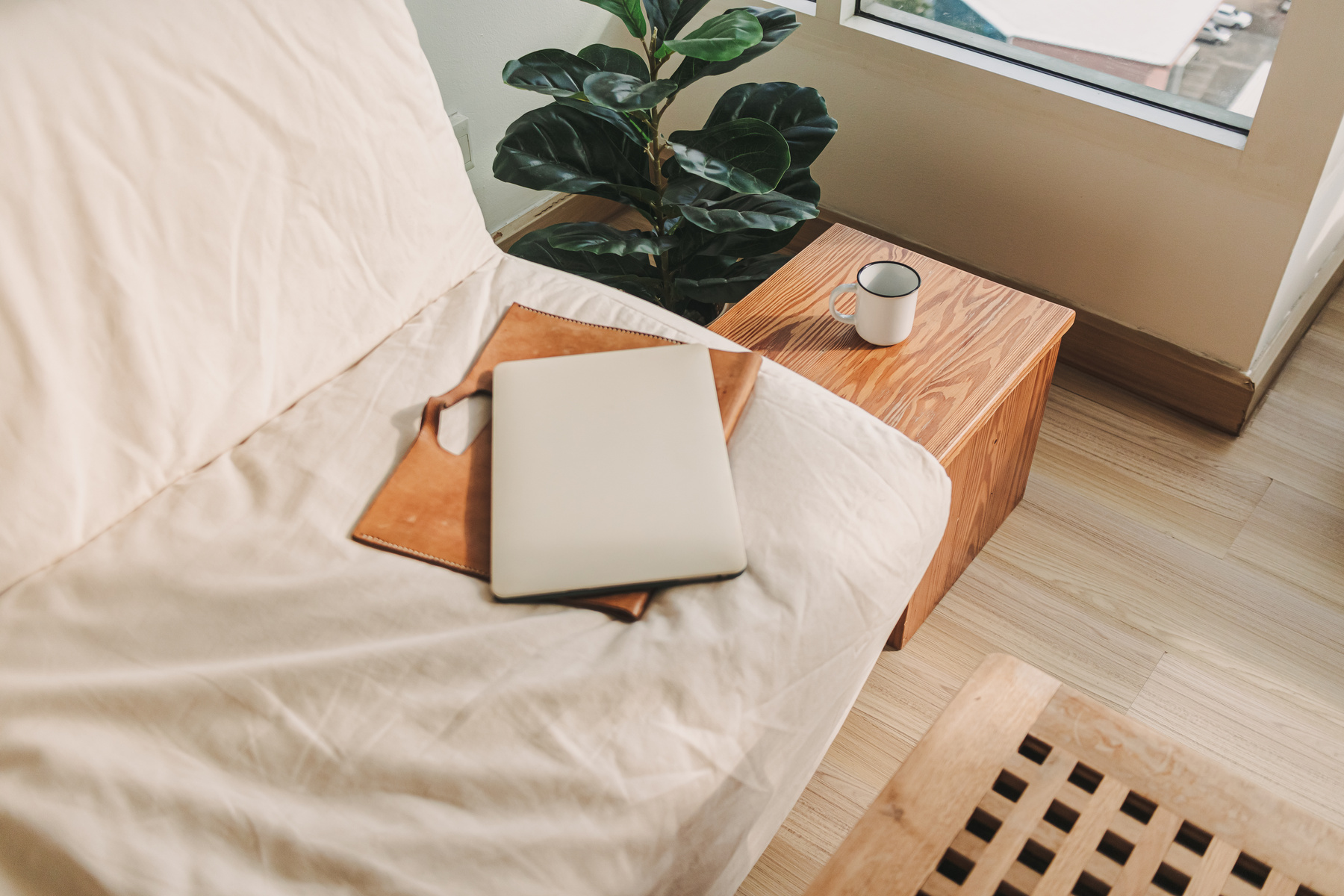 Laptop with Leather Sleeve on Beige Sofa in the Living Room.